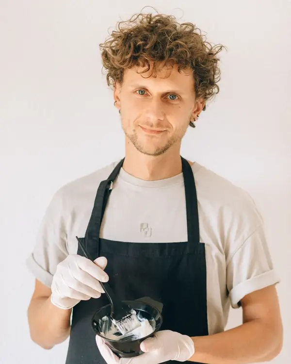 Friseur mit Locken und schwarzer Schürze