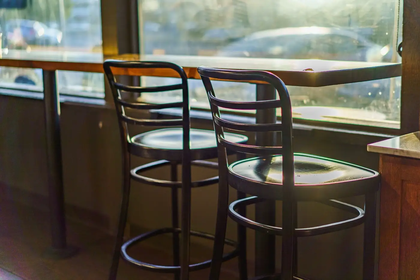 Zwei Stühle am sonnigen Fenster eines Cafés