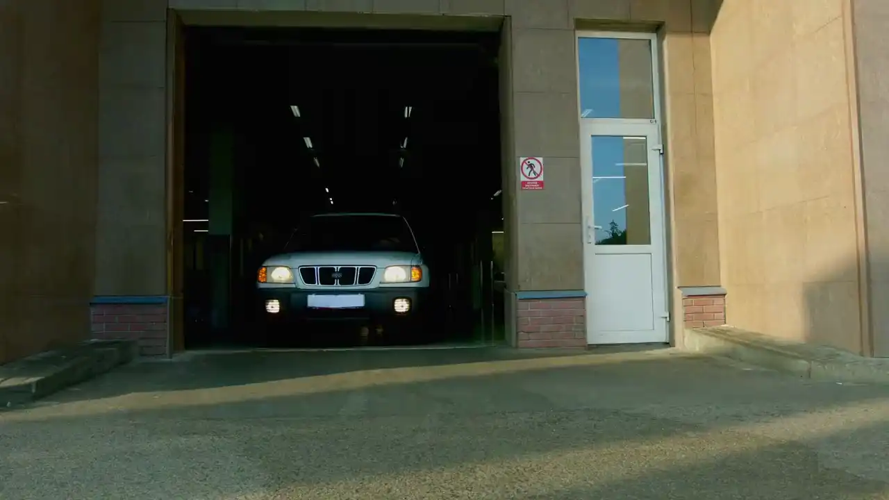 Ein Auto fährt mit eingeschaltetem Licht aus dem offenen Werkstatttor