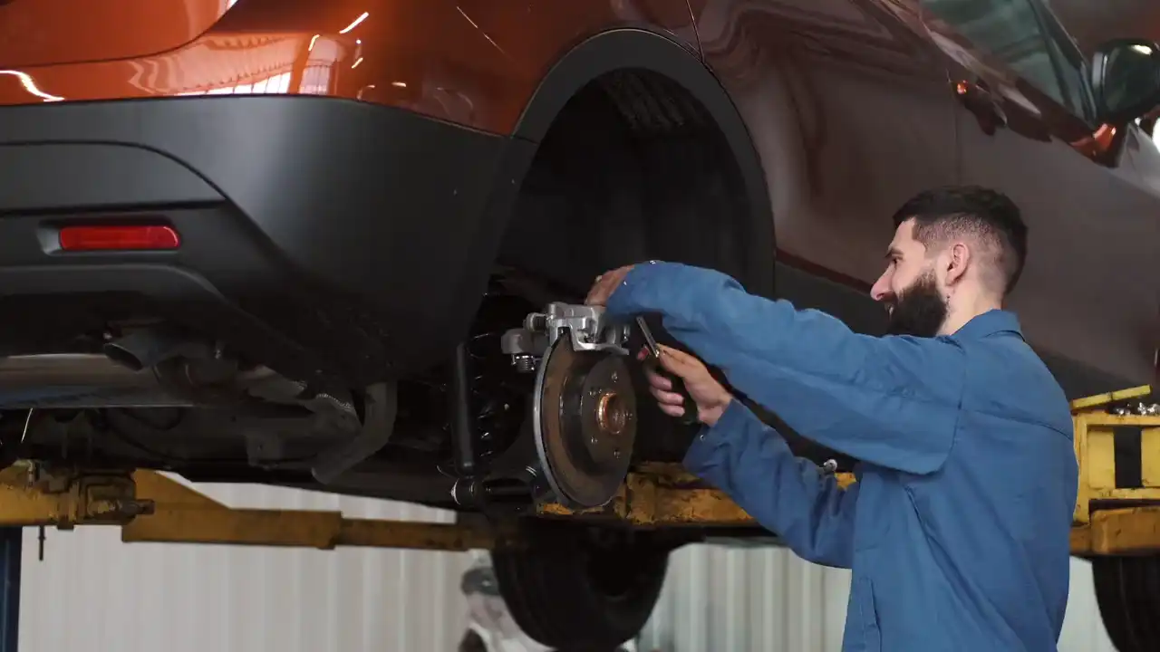 Ein Mechaniker arbeitet an der Bremse eines angehobenen Autos