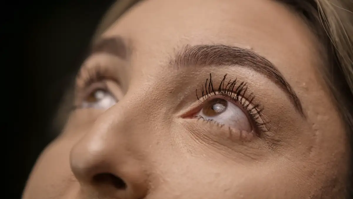 Nahaufnahme eines Auges mit langen, geschwungenen Wimpern, der Blick geht nach oben