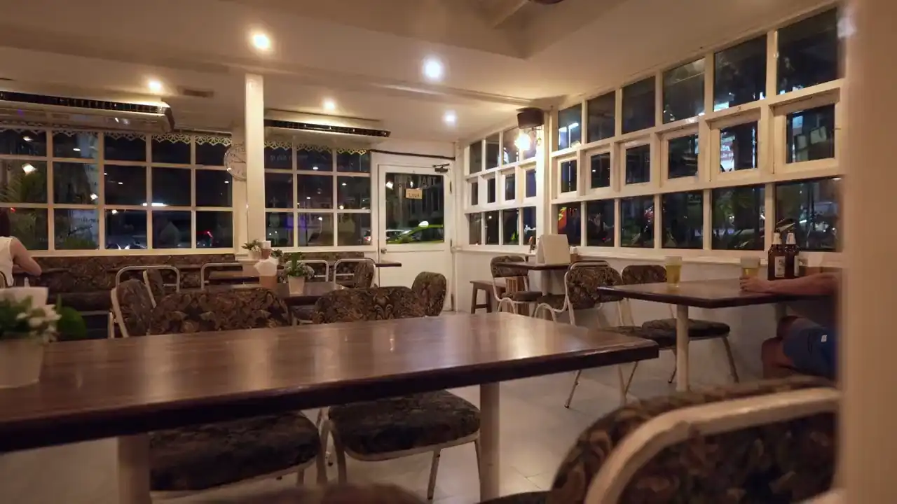 Ein Lokal am Abend mit Holztischen und großen Fenstern